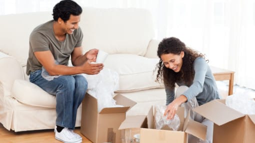 couple packing glasses into cardboard boxes