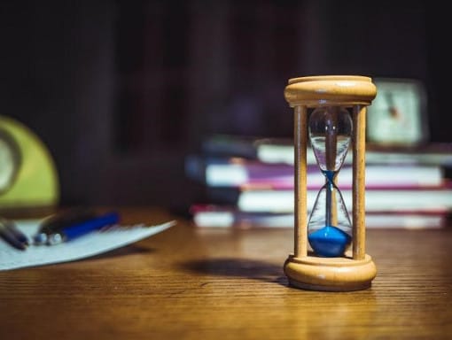 A wooden hourglass with blue sand